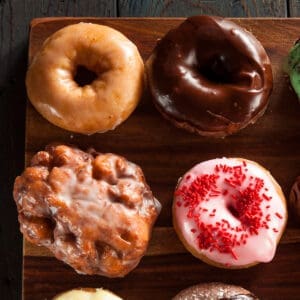 Four donuts on a wooden board.